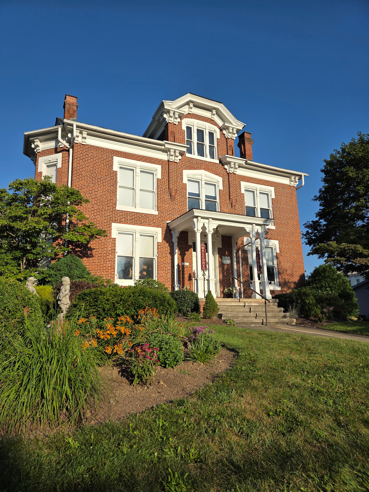 Victorian brick home with white trim and landscaped garden