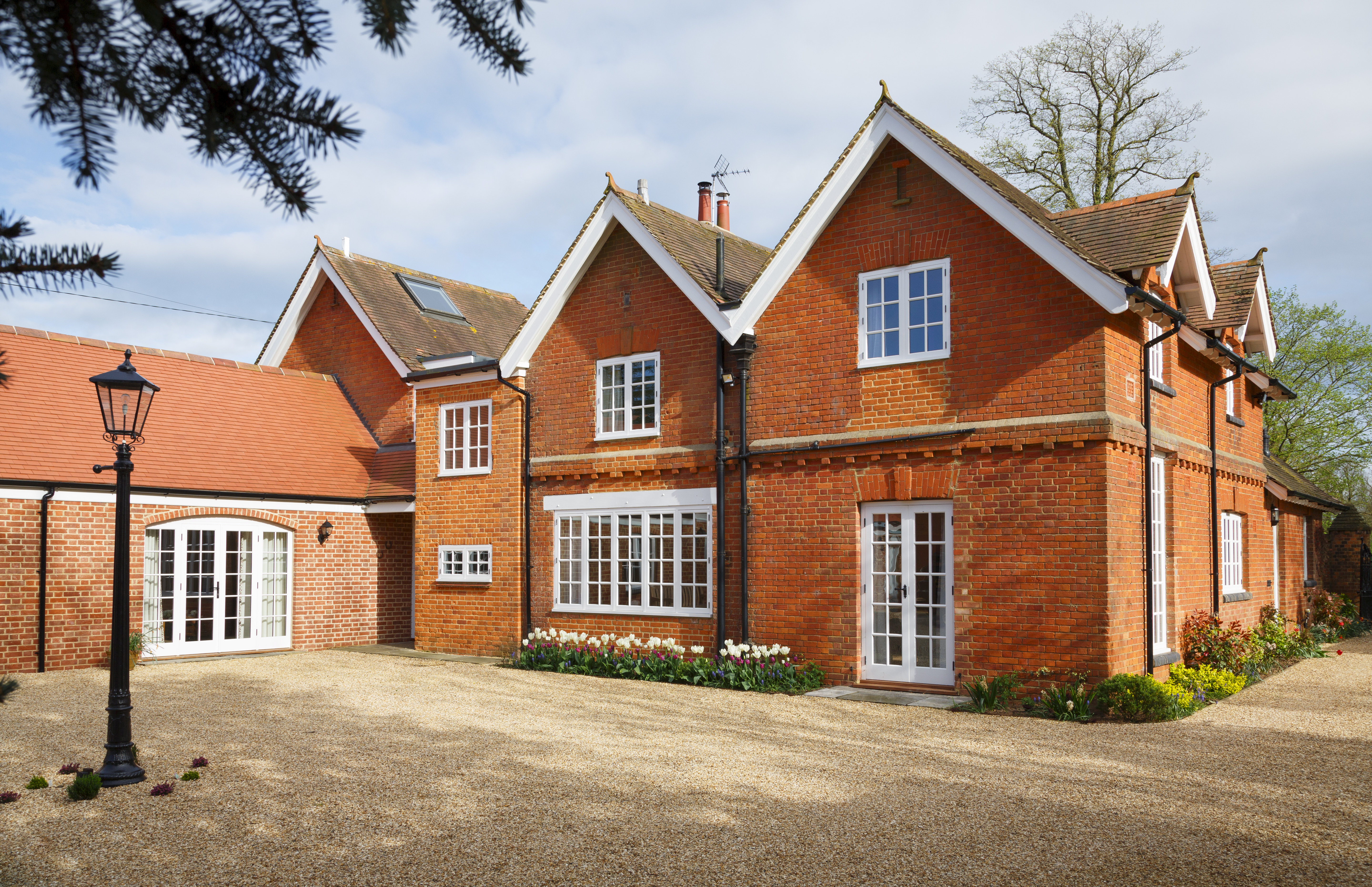 Exterior view of a Victorian home showcasing red brick, gabled roofs, and period windows.