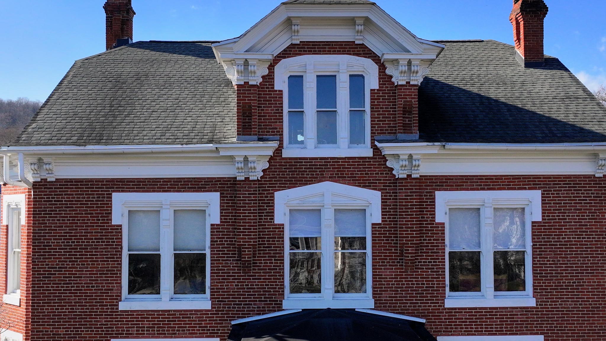 Front facade of the Italianate brick mansion with a central oriel window and bracketed cornices.