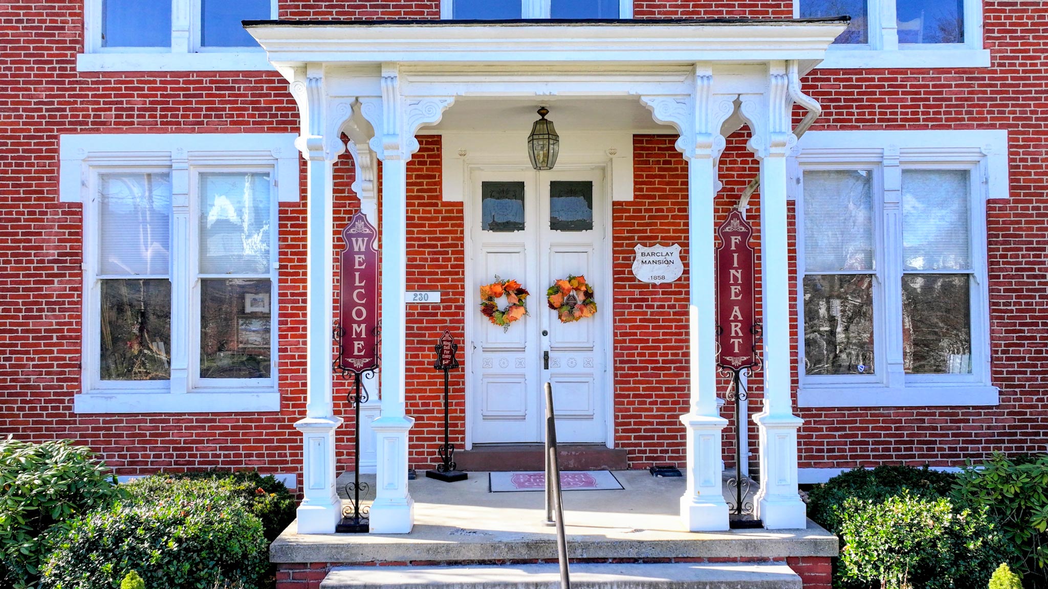 The Barclay Mansion entrance flanked by "Welcome" and "Fine Art" banners at the white double doors.
