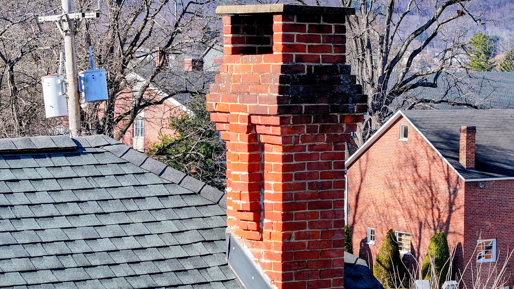 Corbelled red-brick chimney rising from the slate roof above the neighborhood.
