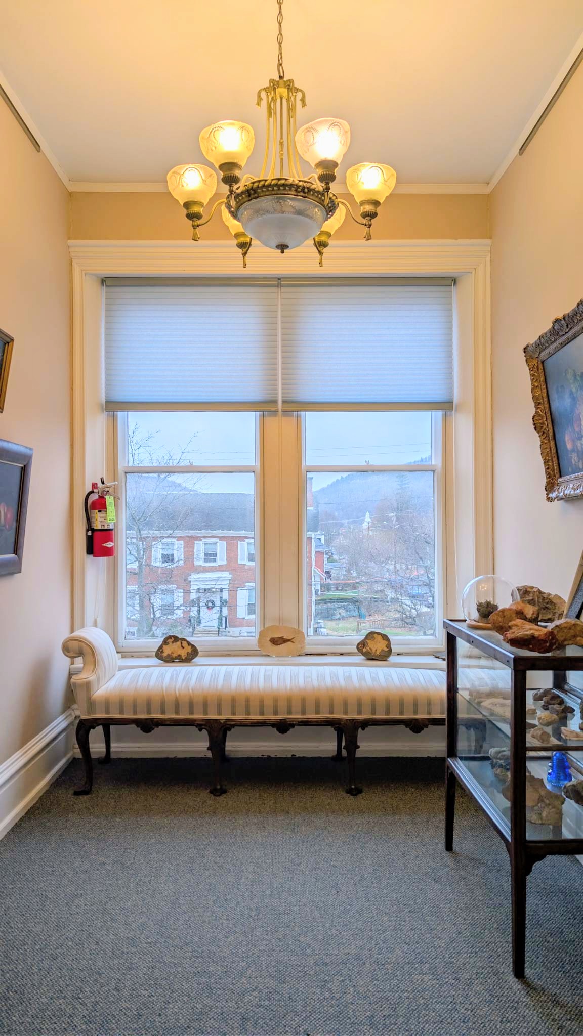Sitting area with a striped window bench beneath tall windows overlooking Bedford's rooftops and mountains.