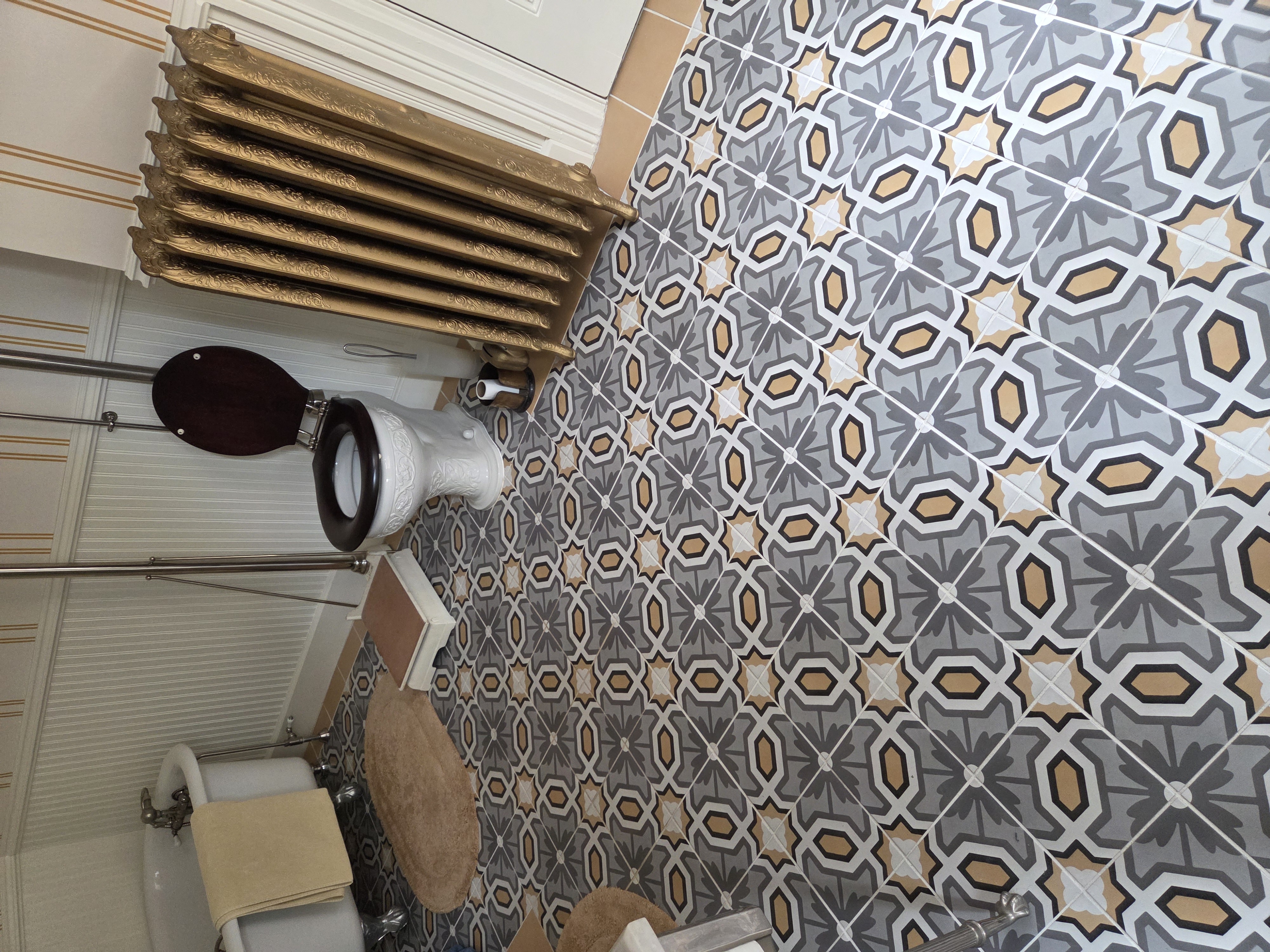 Victorian bathroom featuring patterned tile floor, clawfoot tub, and ornate fixtures